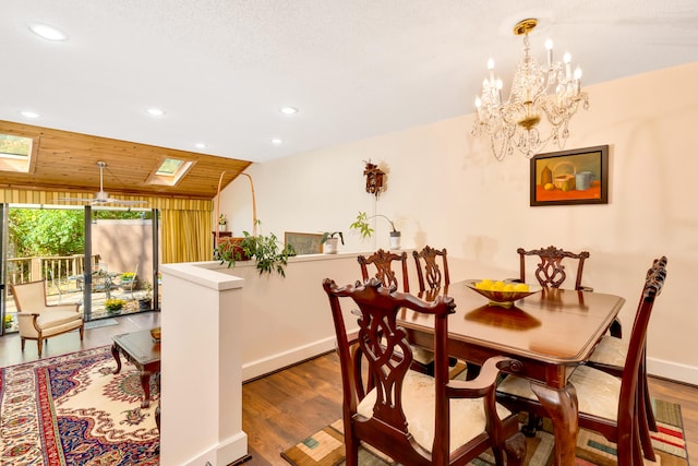 dining room featuring a chandelier, wood-type flooring, a textured ceiling, and a skylight