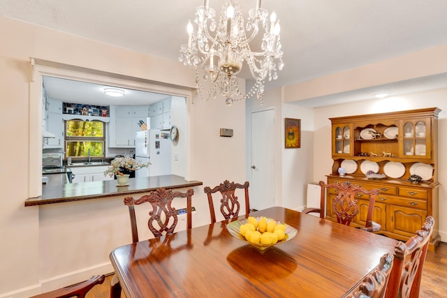 dining area with a notable chandelier, sink, and light wood-type flooring