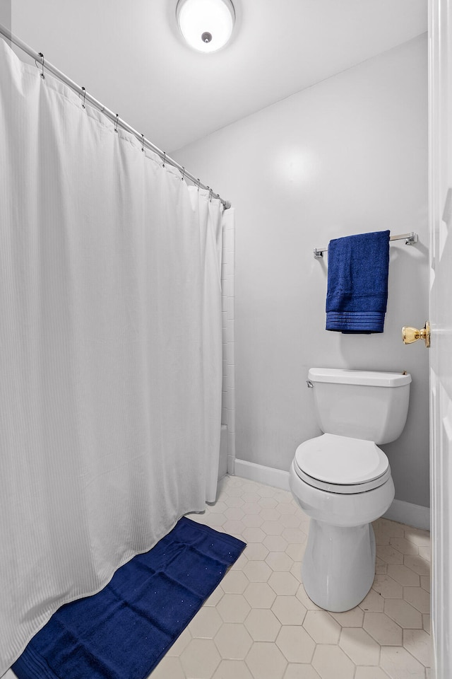 bathroom featuring toilet, tile patterned floors, and walk in shower