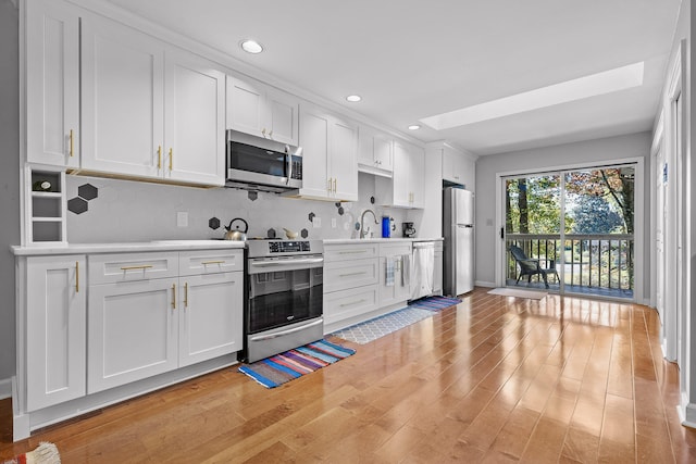 kitchen with white cabinetry, tasteful backsplash, appliances with stainless steel finishes, and light hardwood / wood-style flooring