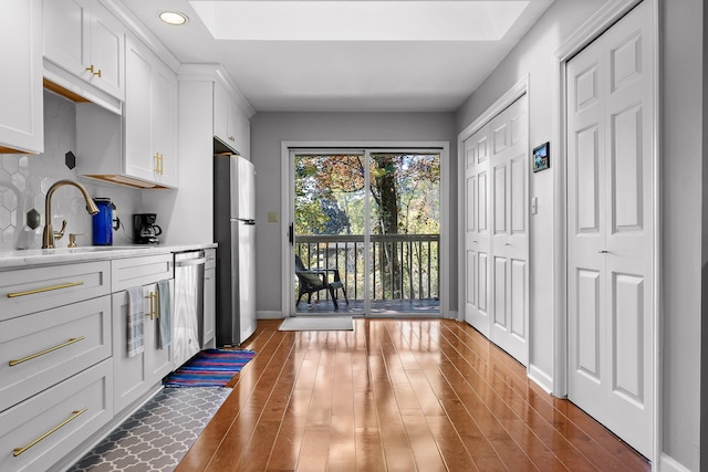 kitchen featuring sink, stainless steel appliances, white cabinets, decorative backsplash, and dark hardwood / wood-style floors