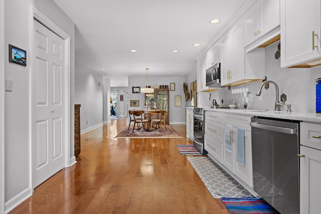 kitchen featuring sink, appliances with stainless steel finishes, wood-type flooring, and white cabinets