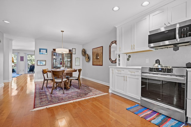 kitchen with appliances with stainless steel finishes, light hardwood / wood-style flooring, and white cabinetry