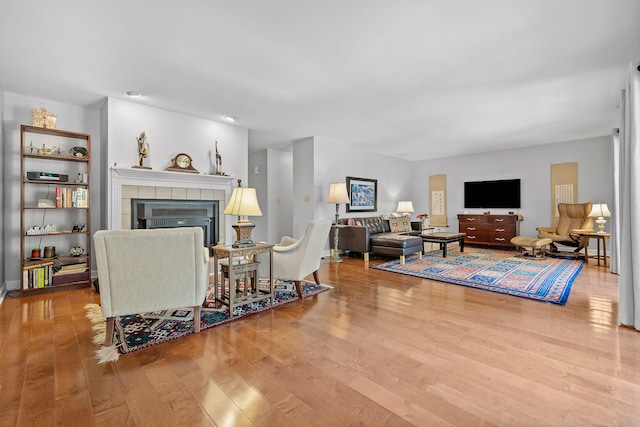 living room with hardwood / wood-style flooring and a tiled fireplace