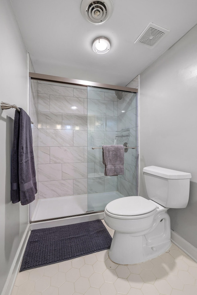 bathroom with toilet, tile patterned floors, and a shower with door