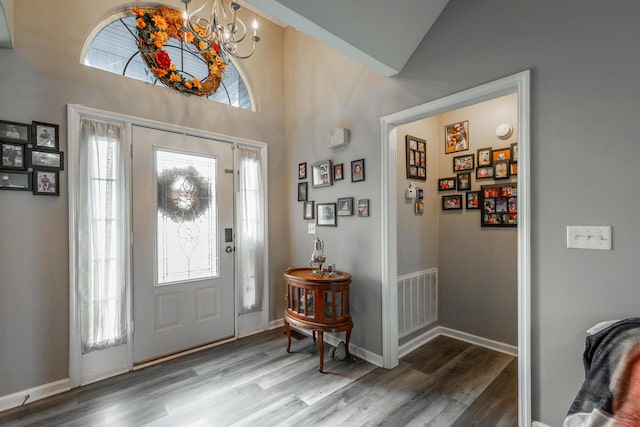 entryway featuring lofted ceiling, wood-type flooring, and a notable chandelier