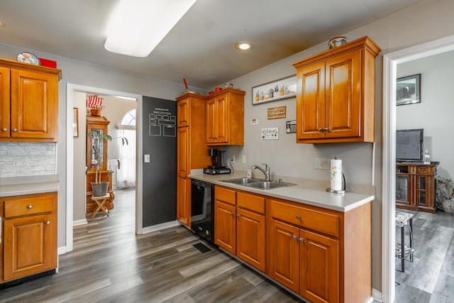 kitchen featuring dark wood-type flooring, black dishwasher, sink, and tasteful backsplash