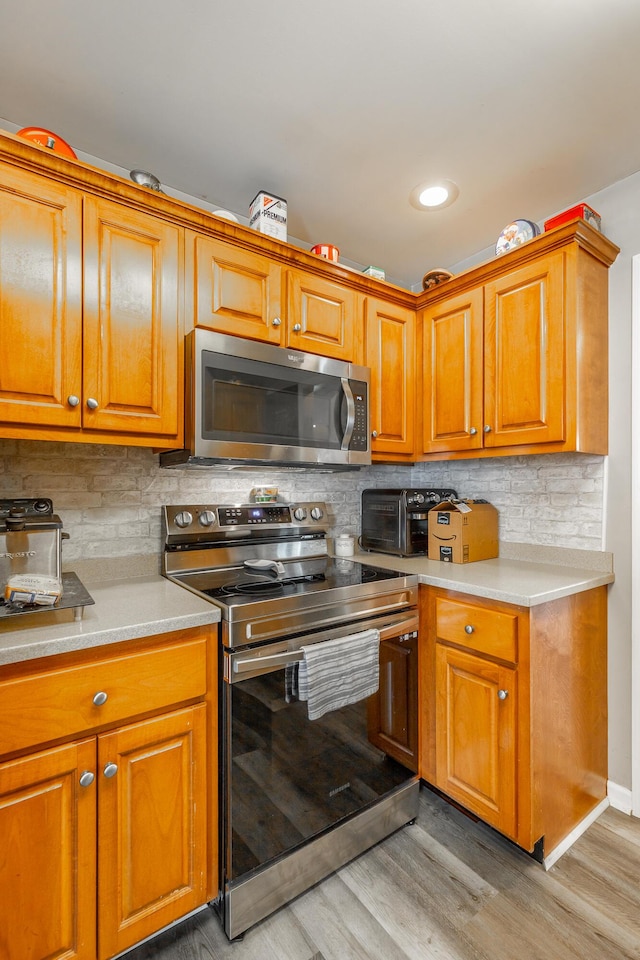 kitchen with tasteful backsplash, light hardwood / wood-style flooring, and appliances with stainless steel finishes