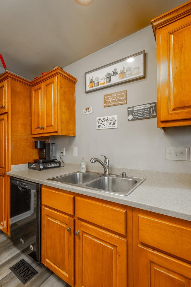 kitchen with black dishwasher, sink, and light hardwood / wood-style flooring