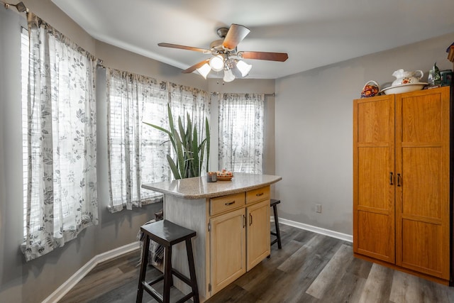 kitchen featuring a kitchen island, a breakfast bar, dark wood-type flooring, and ceiling fan