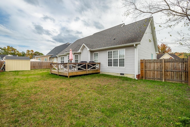 back of property featuring a wooden deck, a yard, and a storage shed