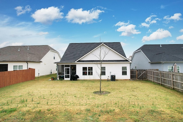 back of property featuring central air condition unit, a sunroom, a fenced backyard, and a lawn