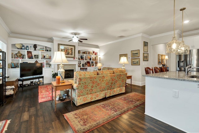 living room featuring dark wood-type flooring, a fireplace, ceiling fan, and ornamental molding