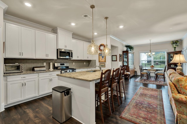 kitchen featuring dark wood-type flooring, pendant lighting, white cabinets, and stainless steel appliances