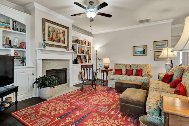 living area with a tile fireplace, visible vents, crown molding, and wood finished floors