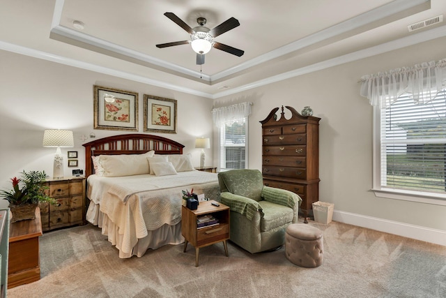 carpeted bedroom featuring visible vents, baseboards, a raised ceiling, and crown molding