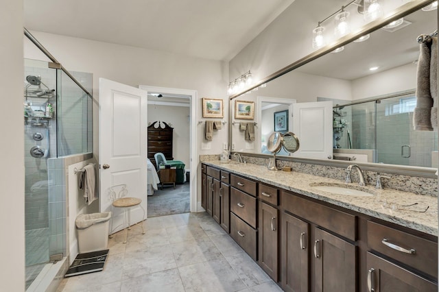 full bathroom with a shower stall, double vanity, a sink, and connected bathroom