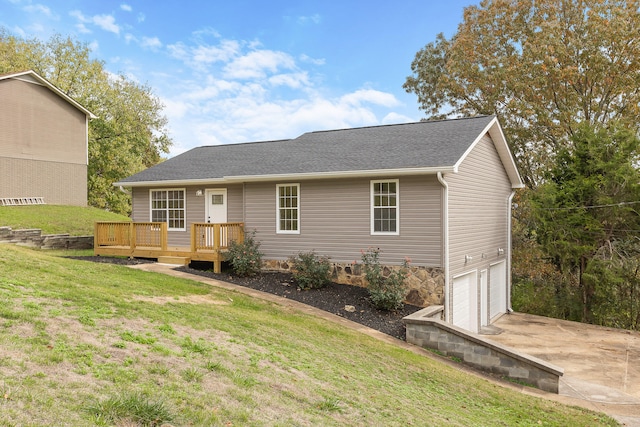 ranch-style home with a garage, a wooden deck, and a front yard