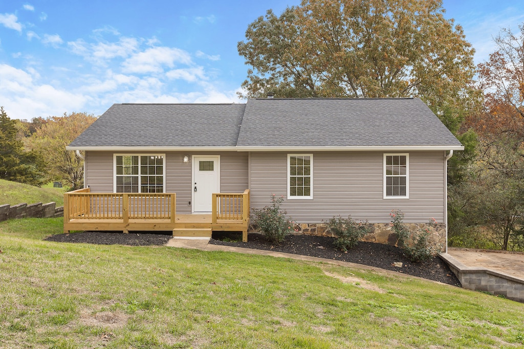 view of front of property featuring a wooden deck and a front lawn