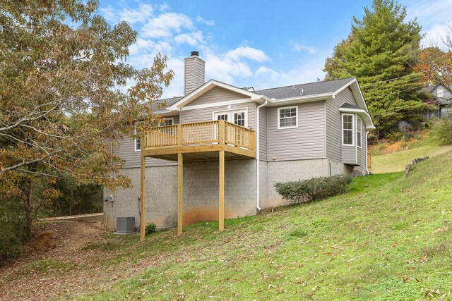 rear view of house with a wooden deck and a lawn