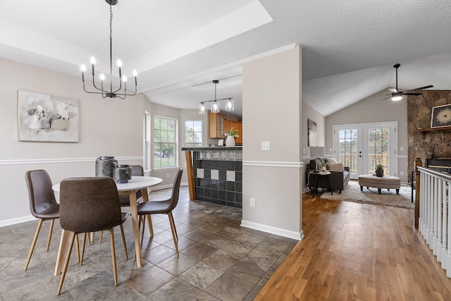 dining space featuring ceiling fan with notable chandelier, a textured ceiling, a stone fireplace, lofted ceiling, and dark wood-type flooring