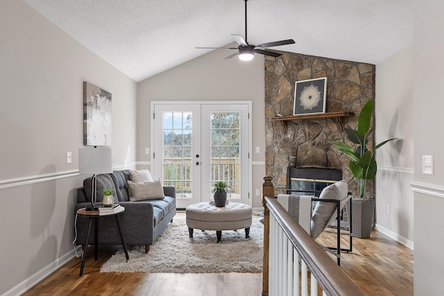 living room featuring vaulted ceiling, a textured ceiling, hardwood / wood-style flooring, ceiling fan, and a fireplace