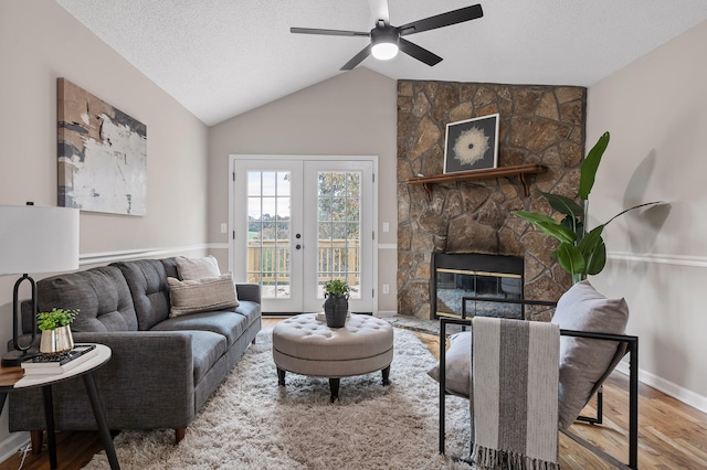 living room with french doors, wood-type flooring, vaulted ceiling, a textured ceiling, and a fireplace