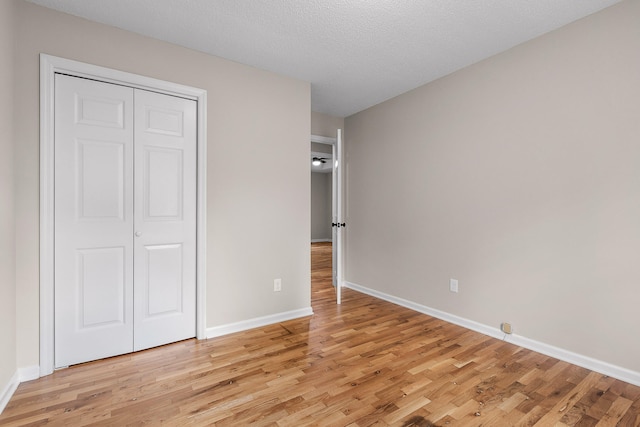 unfurnished bedroom with light hardwood / wood-style flooring, a textured ceiling, and a closet