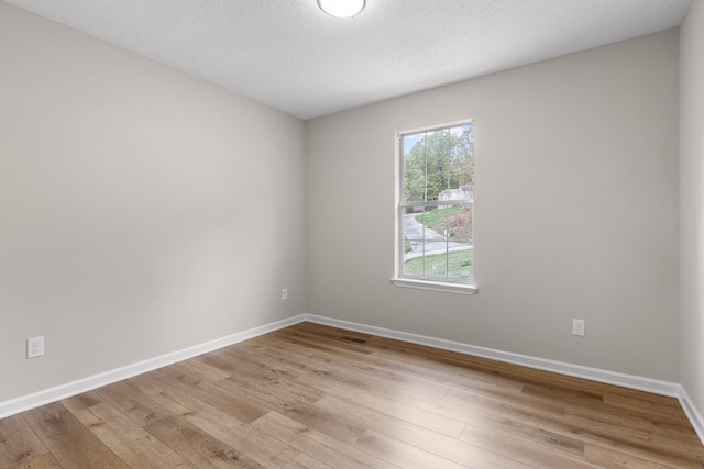 unfurnished room with light wood-type flooring and a textured ceiling