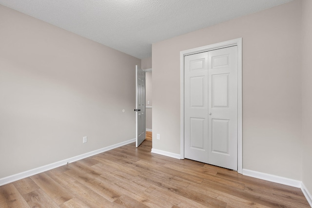 unfurnished bedroom featuring light hardwood / wood-style floors, a textured ceiling, and a closet