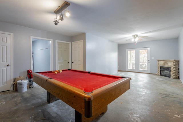 recreation room featuring a stone fireplace, pool table, concrete floors, and ceiling fan