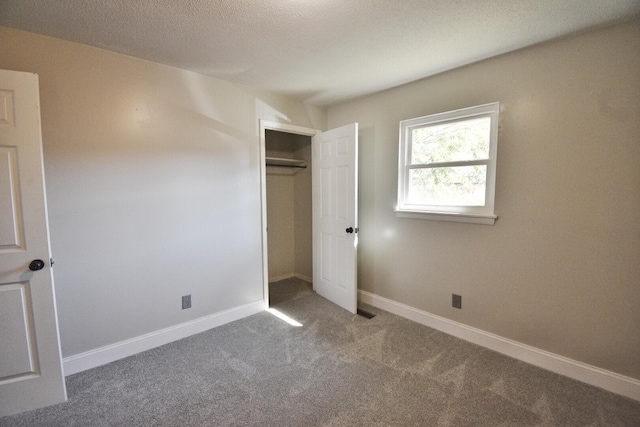 unfurnished bedroom featuring a textured ceiling, carpet floors, and a closet