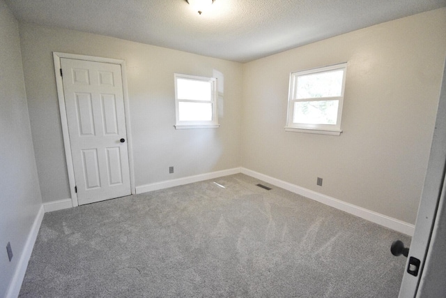 spare room featuring carpet flooring and a textured ceiling