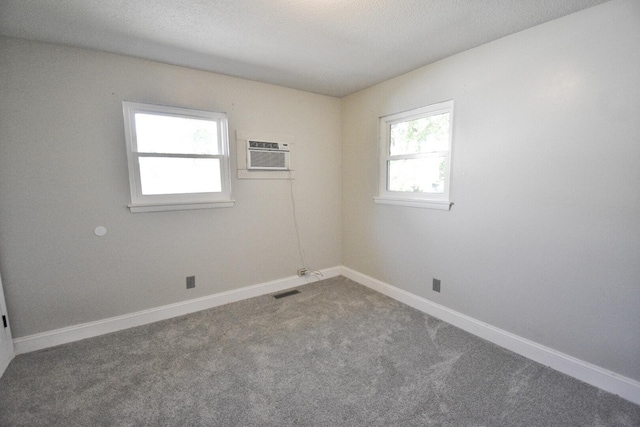 carpeted empty room with a textured ceiling and a wall unit AC