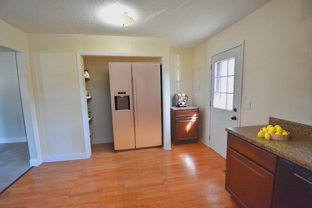 kitchen featuring dishwasher, white refrigerator with ice dispenser, dark stone countertops, a textured ceiling, and light hardwood / wood-style floors