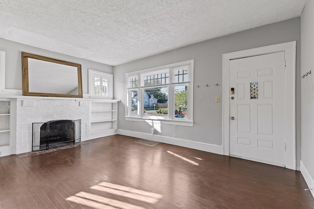 unfurnished living room featuring dark wood-type flooring and a textured ceiling