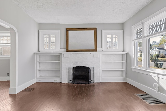 unfurnished living room featuring a textured ceiling, wood-type flooring, and plenty of natural light