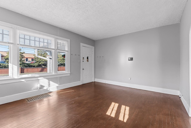 spare room featuring a textured ceiling and dark wood-type flooring