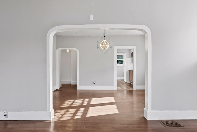 unfurnished dining area featuring a chandelier and dark hardwood / wood-style floors