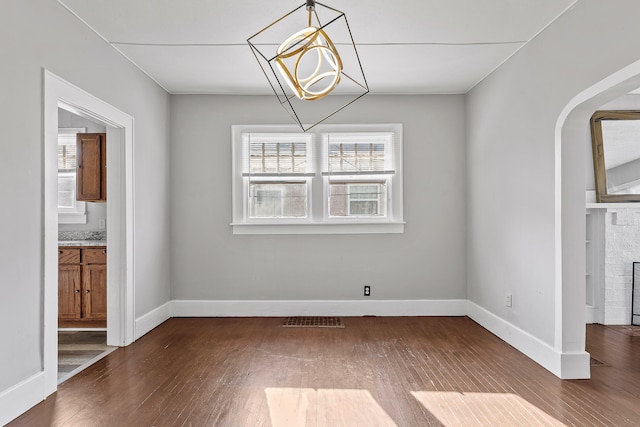 unfurnished dining area with a notable chandelier, hardwood / wood-style floors, and a stone fireplace