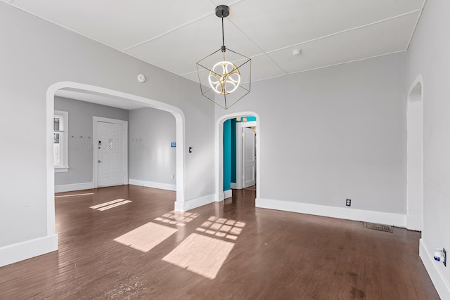 unfurnished room with a chandelier and dark hardwood / wood-style floors