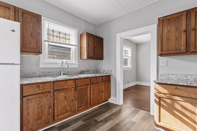 kitchen with sink, light stone countertops, dark hardwood / wood-style flooring, and white refrigerator