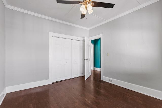 unfurnished bedroom with dark wood-type flooring, ceiling fan, crown molding, and a closet