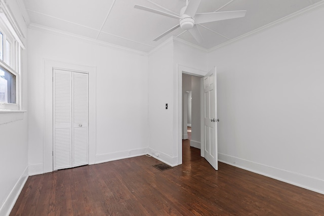 unfurnished bedroom featuring ornamental molding, dark wood-type flooring, a closet, and ceiling fan