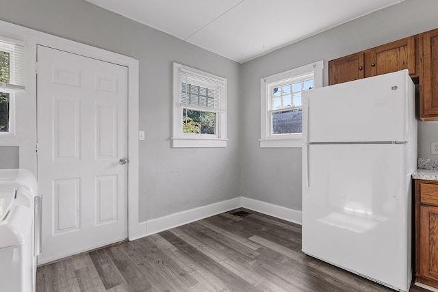 kitchen featuring washer / clothes dryer, a healthy amount of sunlight, white fridge, and hardwood / wood-style floors