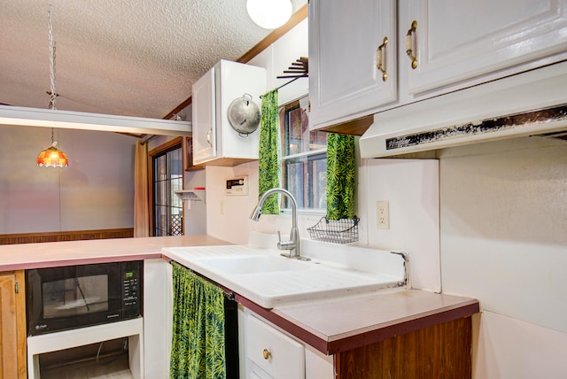 kitchen with a textured ceiling, decorative light fixtures, and white cabinets