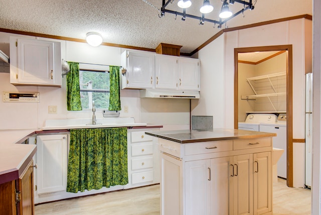 kitchen featuring crown molding, light wood-type flooring, a textured ceiling, white cabinets, and washer and dryer