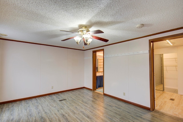 unfurnished bedroom with a textured ceiling, ensuite bathroom, hardwood / wood-style flooring, and ceiling fan