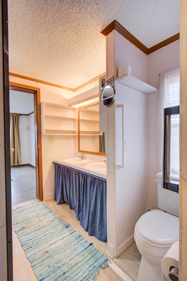 bathroom with toilet, sink, a textured ceiling, and crown molding