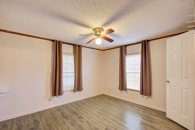 unfurnished room with ornamental molding, plenty of natural light, wood-type flooring, and a textured ceiling